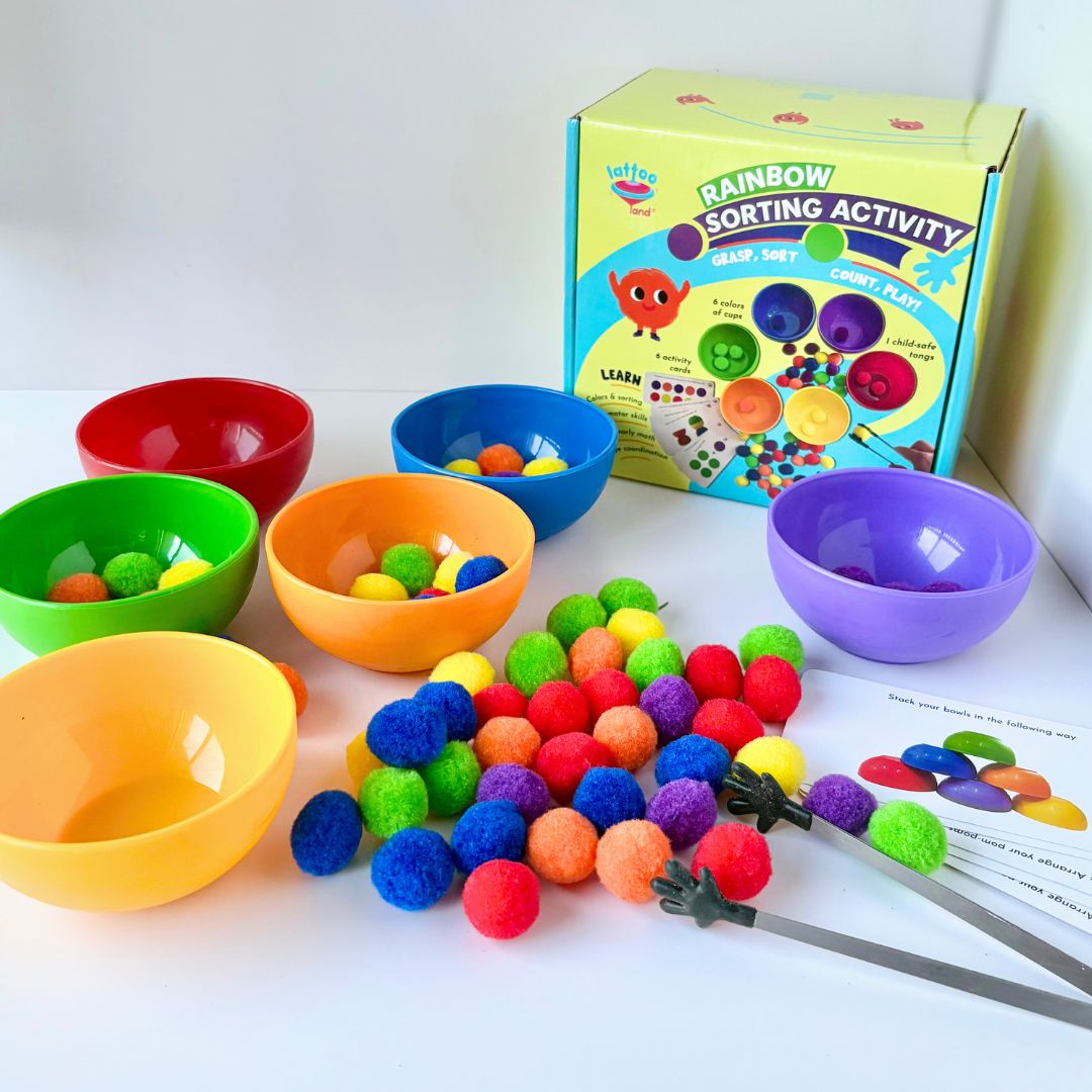 Sorting activity for preschoolers with vibrant rainbow pompoms and cups  to encourage cognitive development with six plastic cups in red, orange, green, yellow, blue, and purple, along with a variety of multicolored pompoms and a child-safe tong, displayed alongside its packaging box.