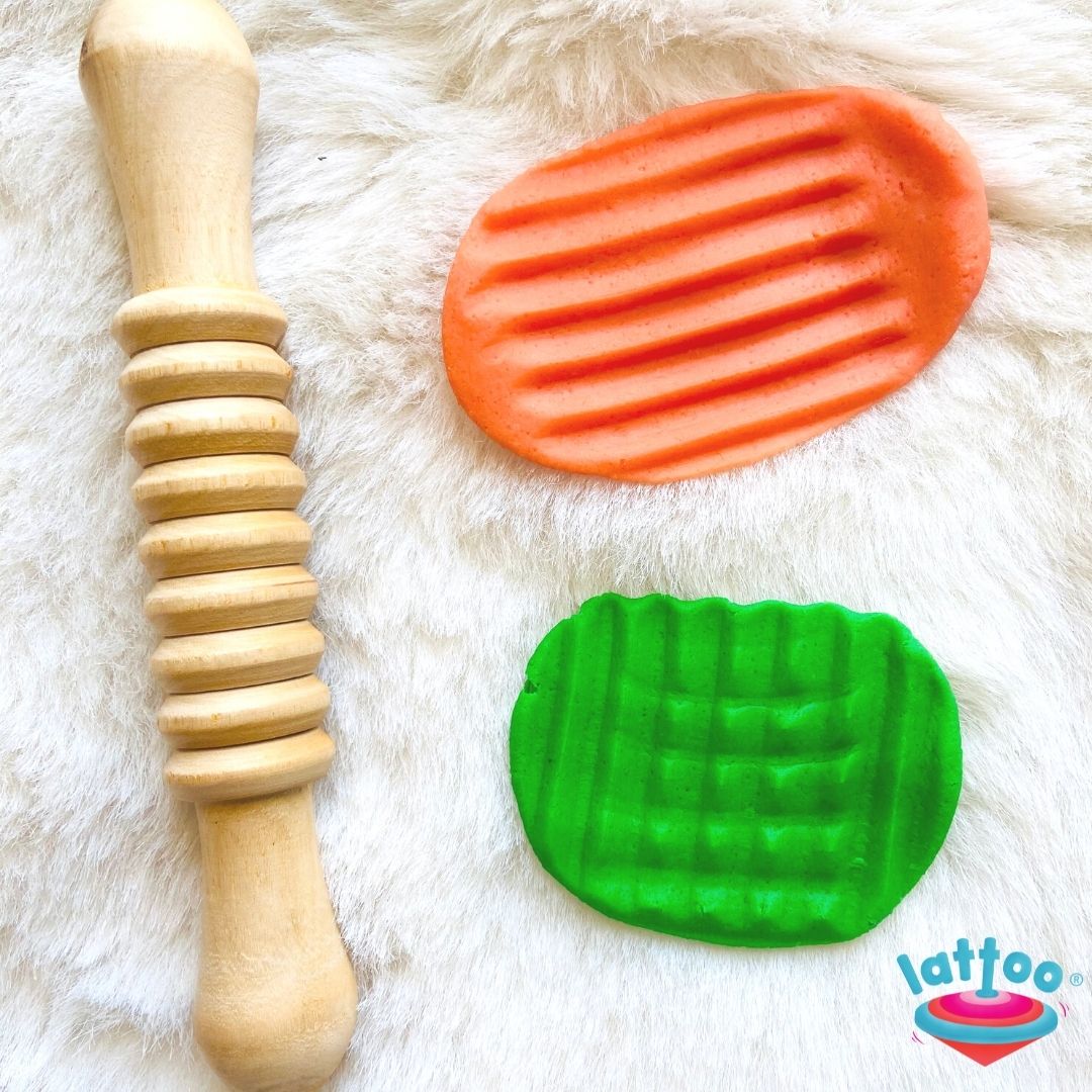 Rolling pin with rings pattern, orange and green colored dough with some patterned impressions